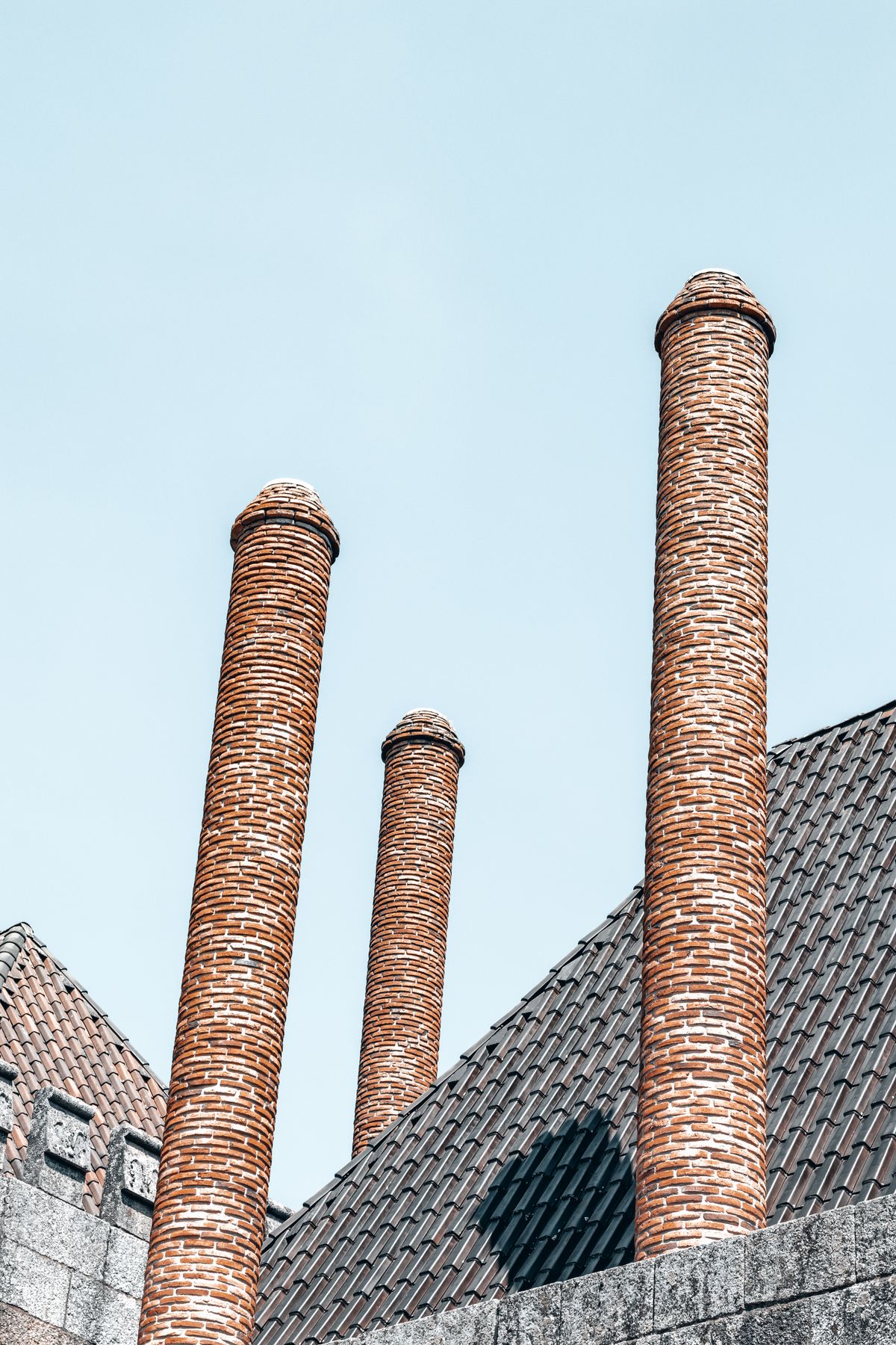 Tall brick chimneys on a rooftop under a clear sky