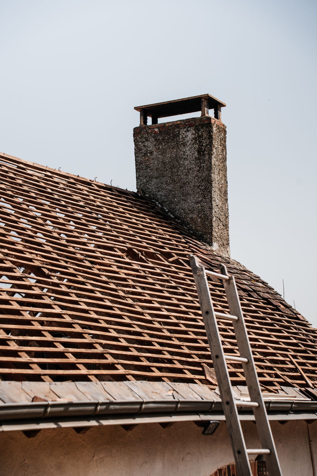Rooftop under renovation with a chimney and ladder