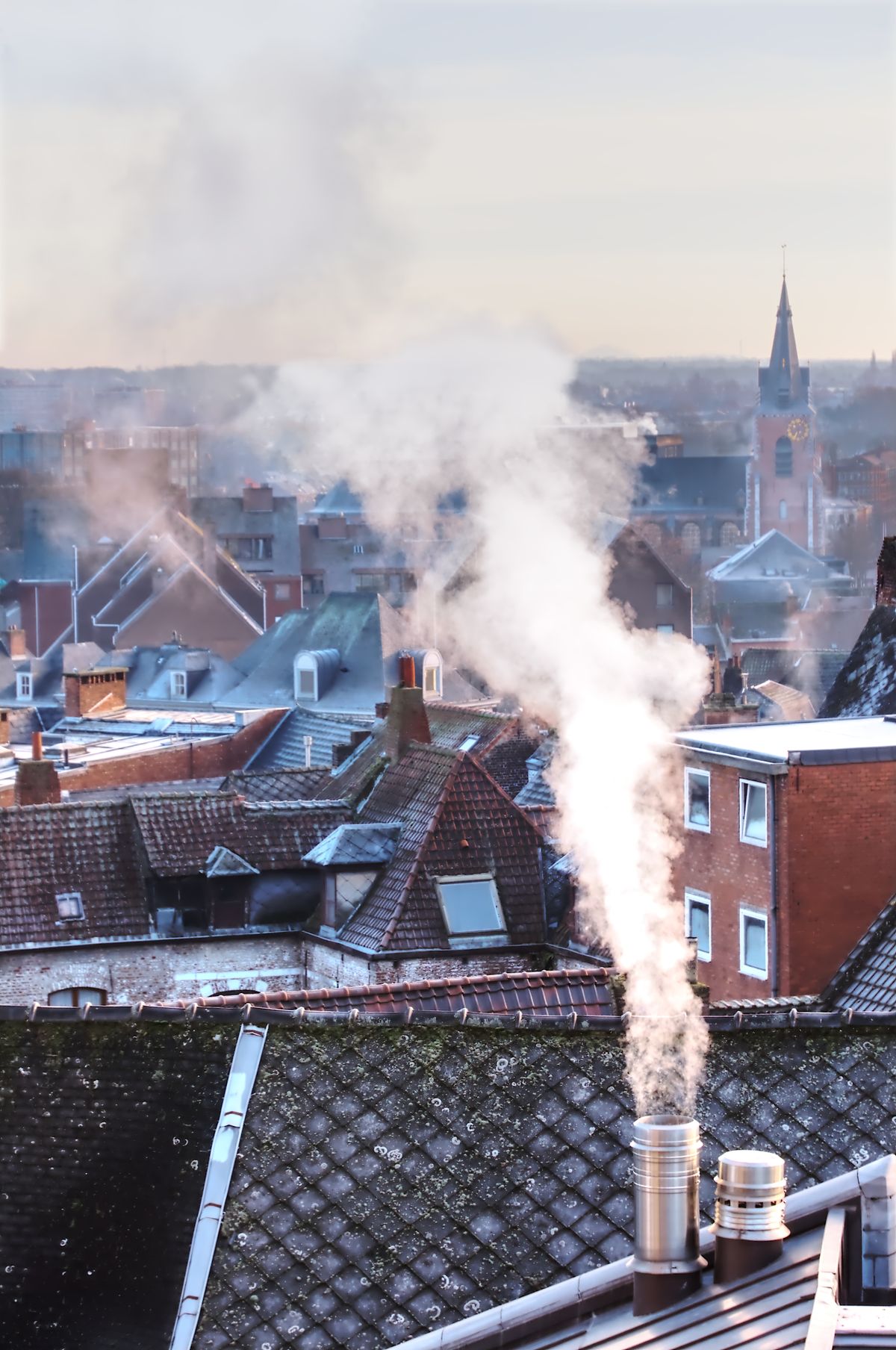 Chimney smoke rising over winter rooftops