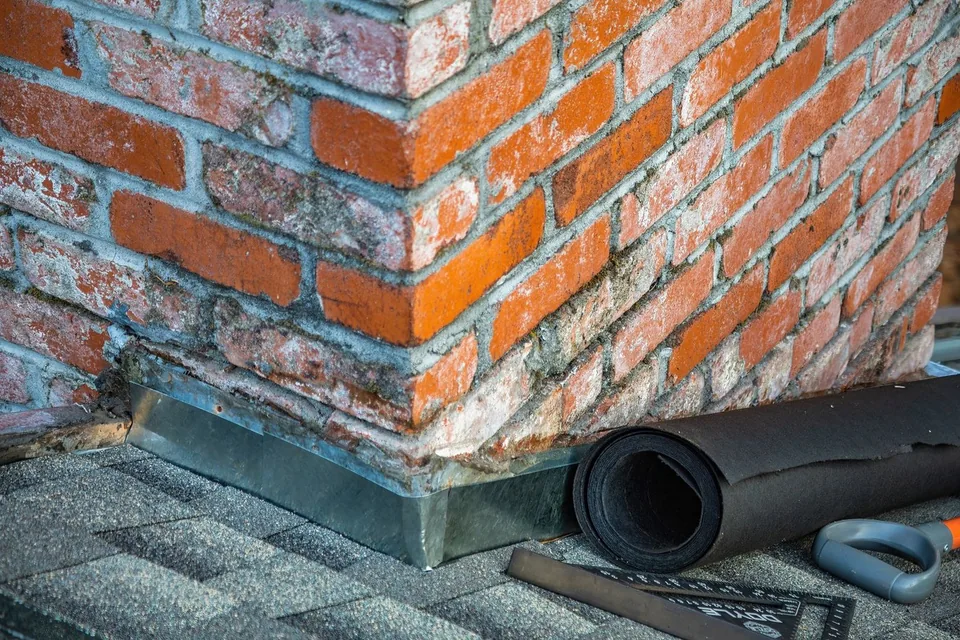 Flashing at the base of a brick chimney on a shingle roof