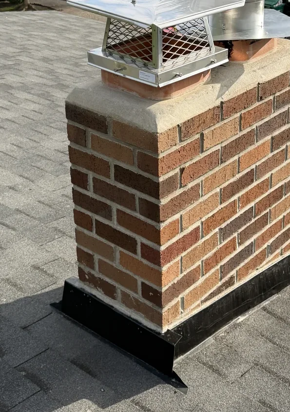 The same chimney rebuilt with fresh brick, a new concrete crown, cap and flashing
